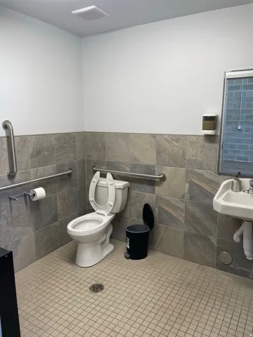 Restroom with wall-mounted sink, ceramic tiled floor, and gray stone-look wall tiling
