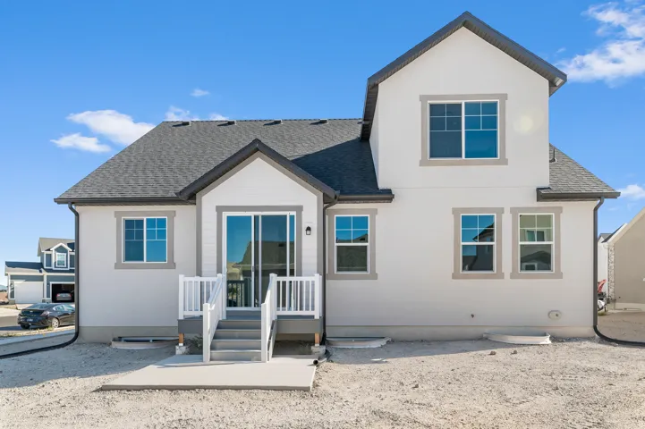Stucco exterior with a pitched roof, multiple windows with contrasting trim, and a patio with a sliding glass door