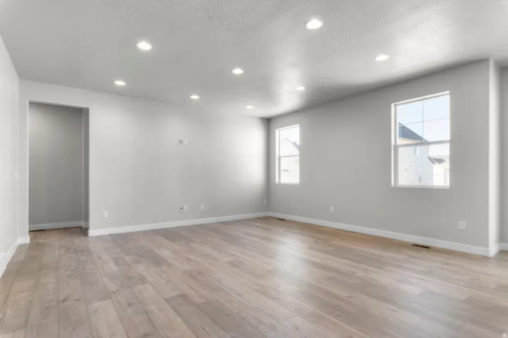 Recessed ceiling lighting, light wood-finish flooring, and multiple windows