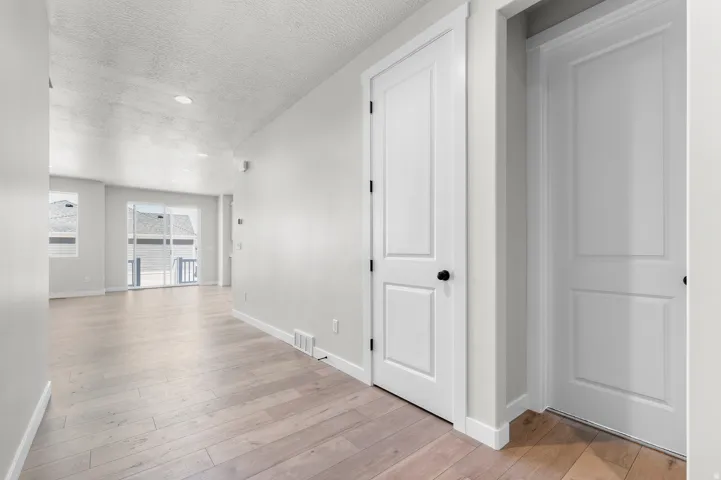 Wood-finish flooring throughout, white interior doors, recessed lighting, and a sliding glass door