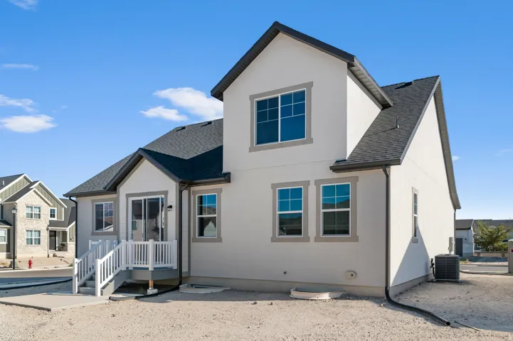Stucco exterior featuring multiple windows with trim, a sliding glass door, an exterior deck with white railing and steps, and an asphalt shingle roof