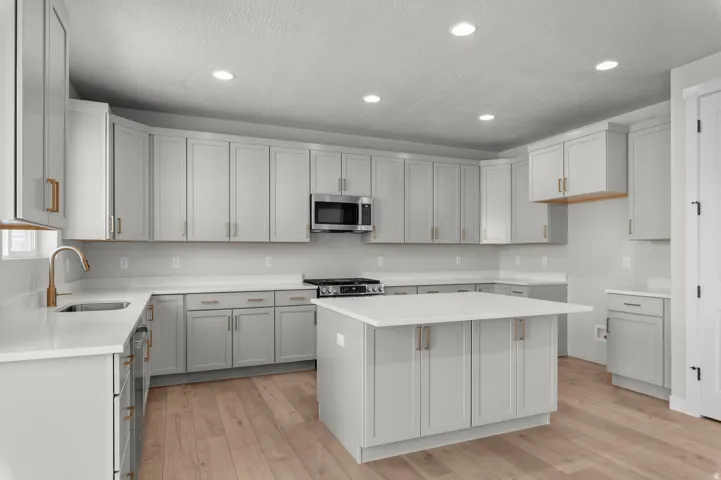 Spacious kitchen featuring an expansive island, light wood-finish flooring, recessed lighting, and stainless steel appliances
