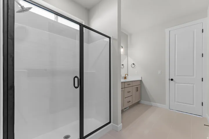 Walk-in shower with black-framed glass enclosure, shower bench, and rainfall showerhead
