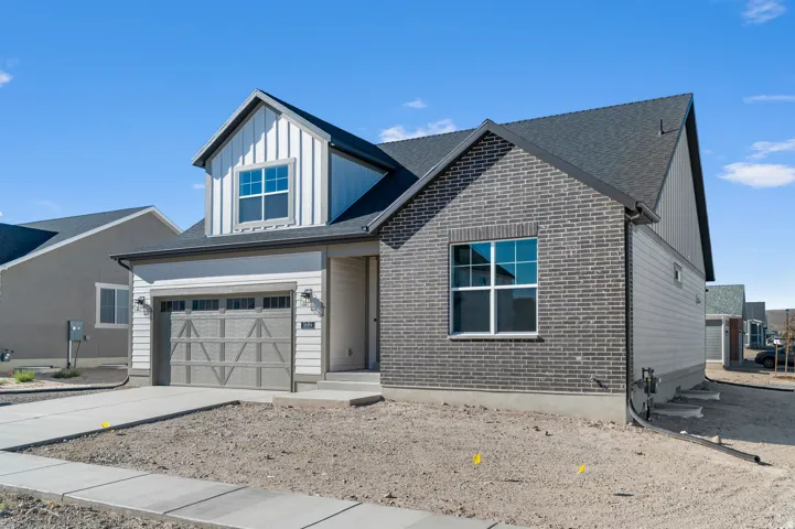 Contemporary exterior with dark brick accents, vertical siding, horizontal siding, attached garage, and concrete driveway