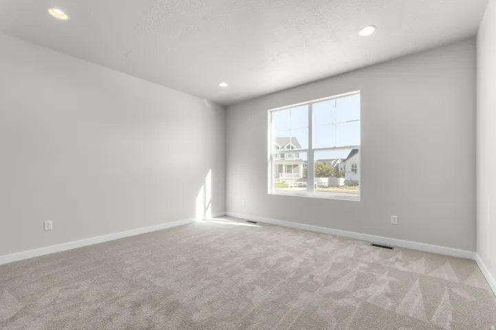 Spacious room featuring neutral carpet flooring, recessed lighting, and a large multi-pane window