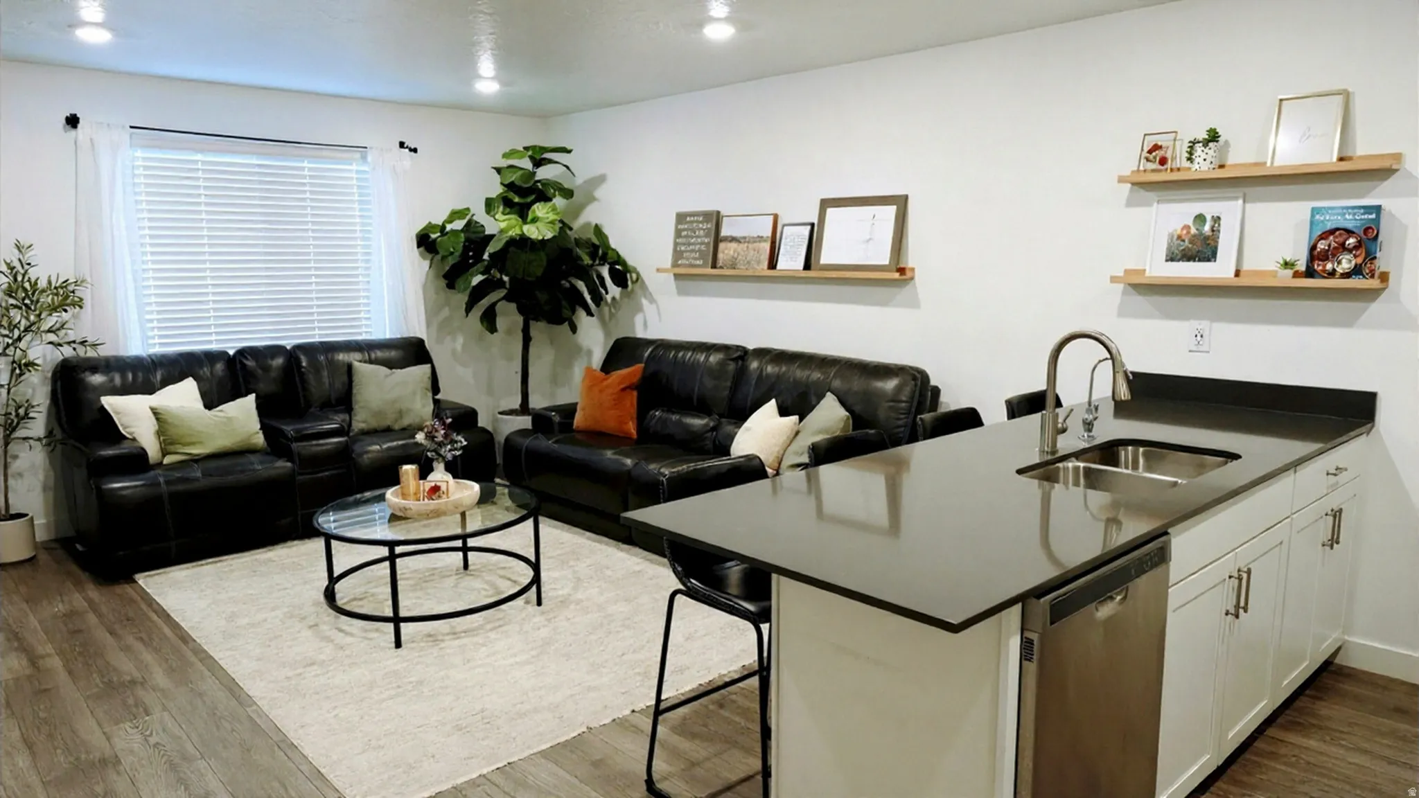 Open-concept living area with wood-finish flooring, white walls, and recessed lighting