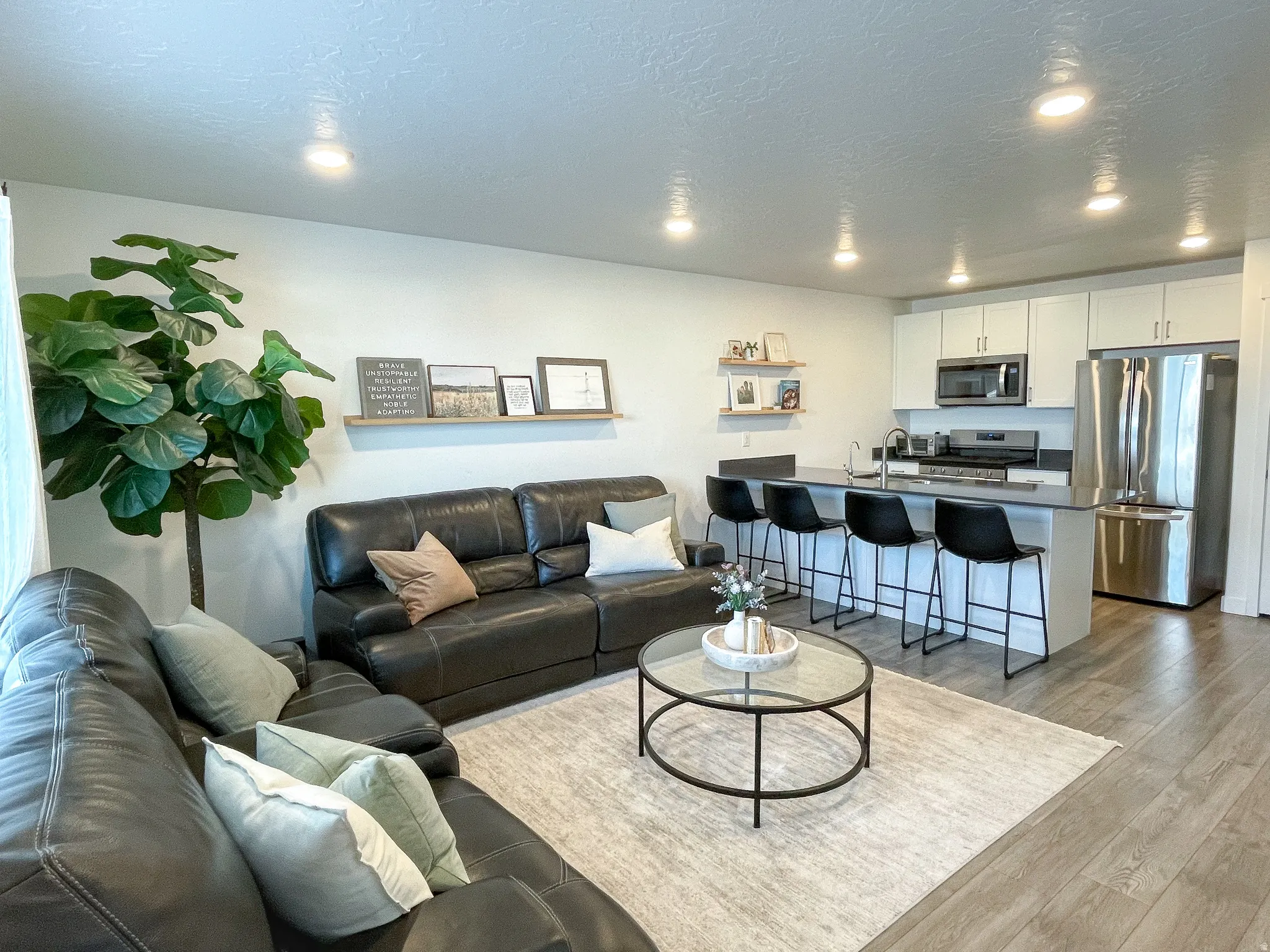 Open-concept living area featuring wood-finish flooring, recessed lighting, and a kitchen island with seating