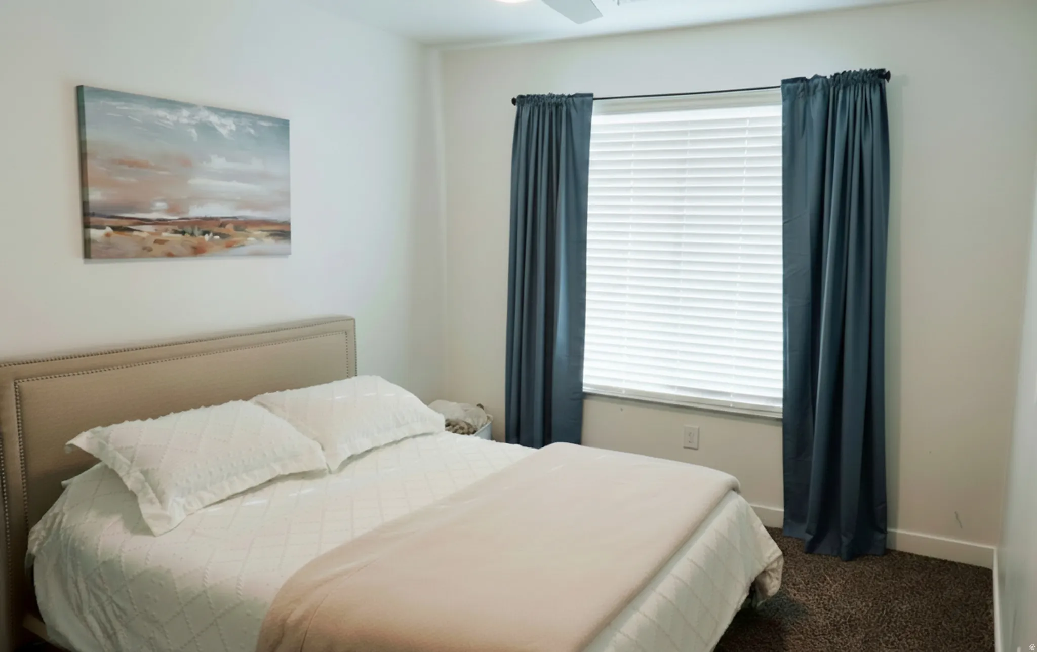 Bright room featuring a window with horizontal blinds and teal curtains, neutral wall paint, and a ceiling fan