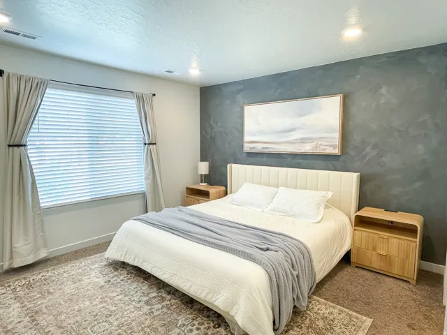 Bedroom featuring a textured accent wall and recessed lighting