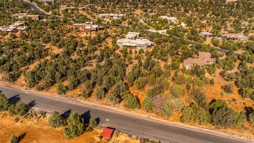 Expansive property featuring a paved road frontage, natural landscaping with mature trees, and multiple residential structures integrated into the hillside terrain