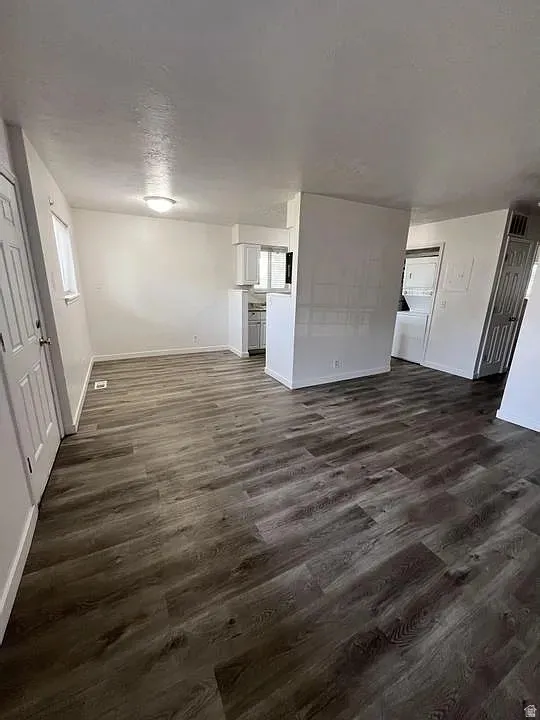 Open-concept living area featuring wood-finish flooring, white walls, and a ceiling-mounted light fixture