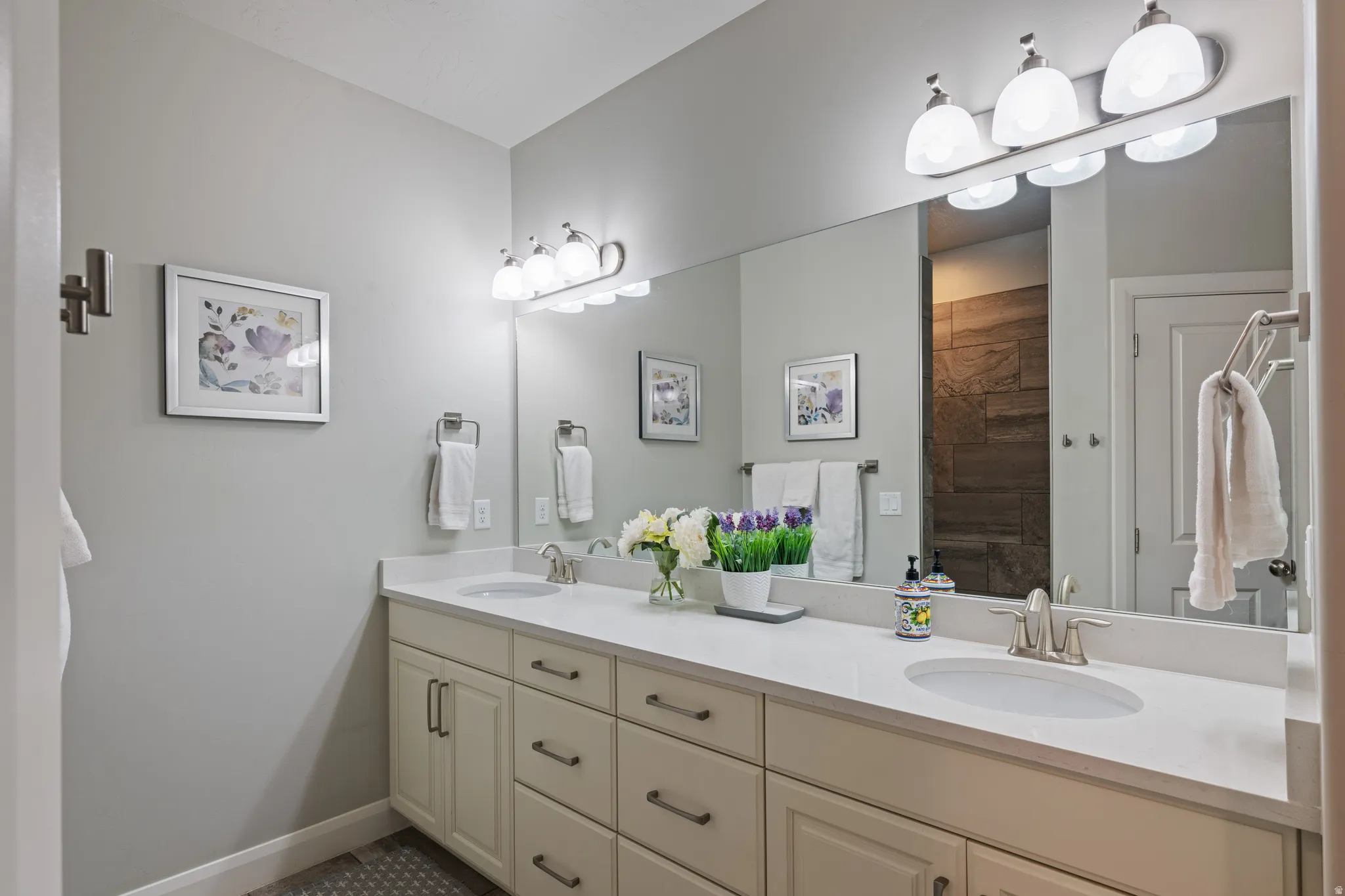 Dual vanity featuring a white countertop with integrated sinks, brushed nickel faucets, and matching lighting fixtures