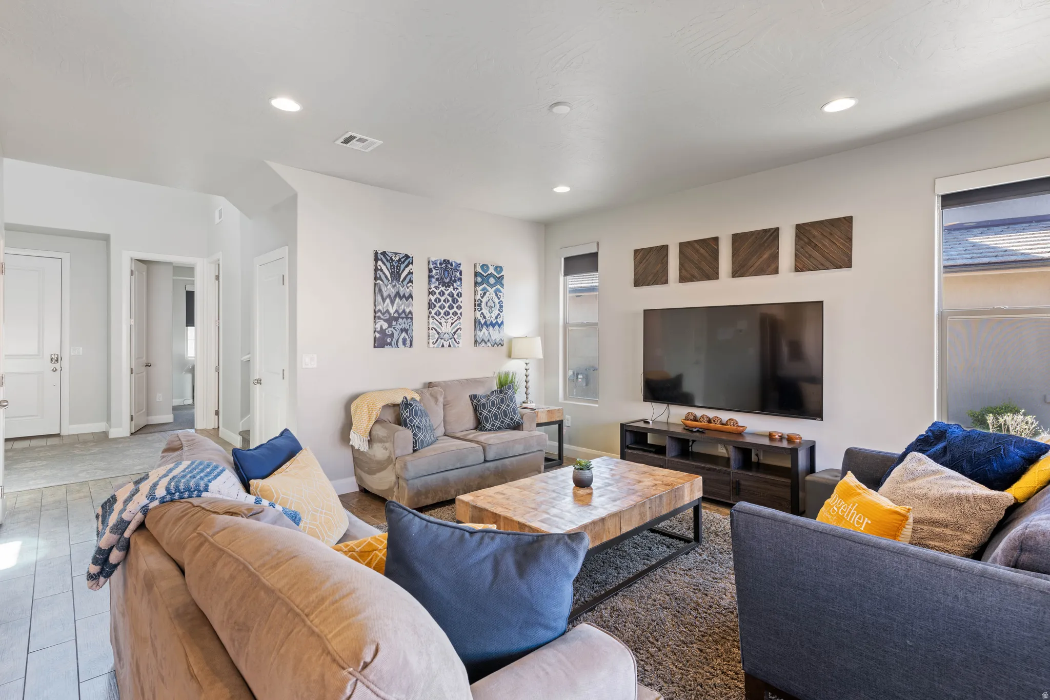 Spacious living area featuring light-toned walls, recessed lighting, and multiple windows