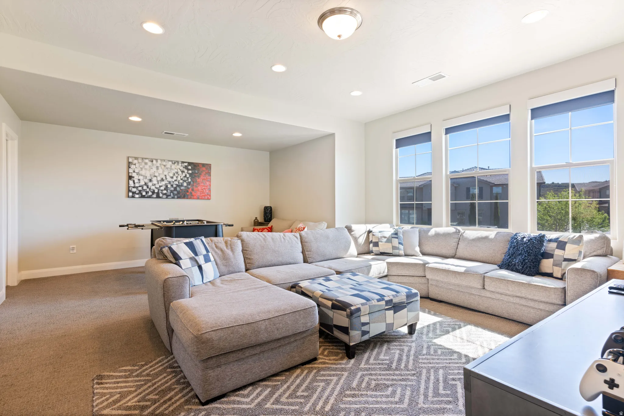Spacious room featuring multiple large windows, recessed ceiling lighting, a contemporary ceiling fixture, and neutral wall tones
