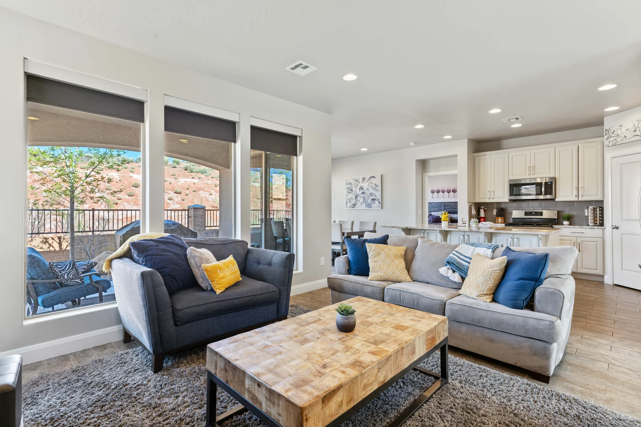 Open-concept living space featuring large windows, recessed lighting, wood-finish flooring, a kitchen with light cabinetry, and an integrated kitchen island