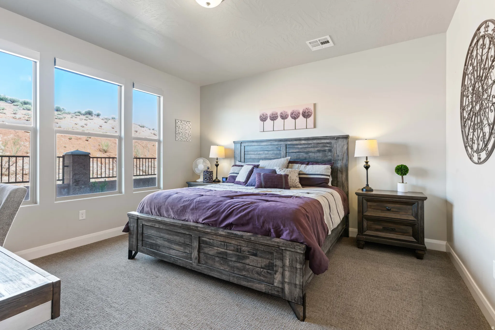 Carpeted room featuring multiple large windows, offering natural light and desert landscape