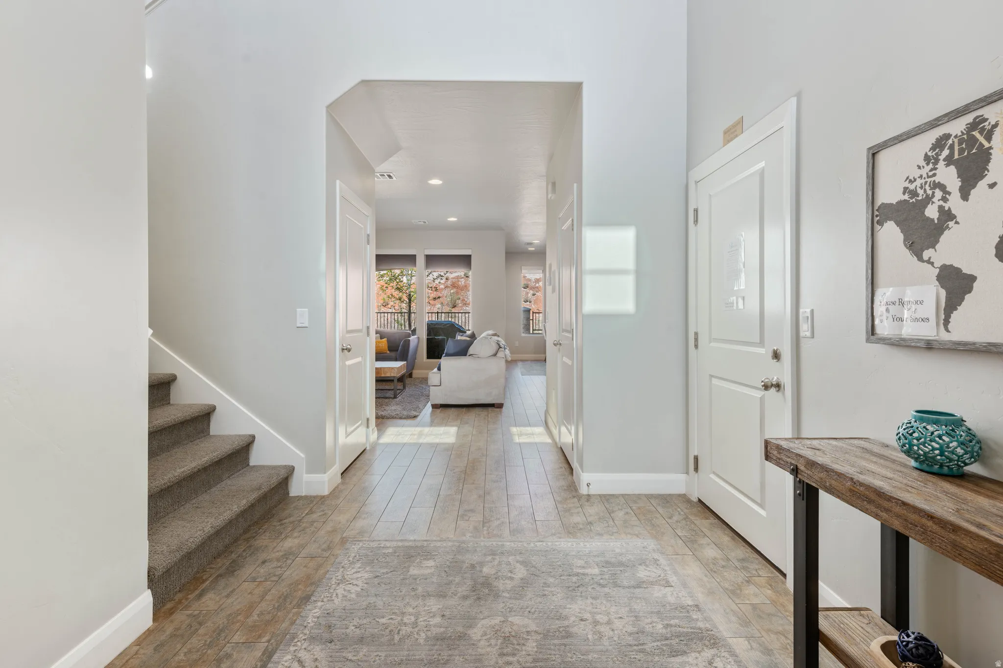 Entryway featuring wood-finish flooring, light grey wall paint, white trim, and a carpeted staircase