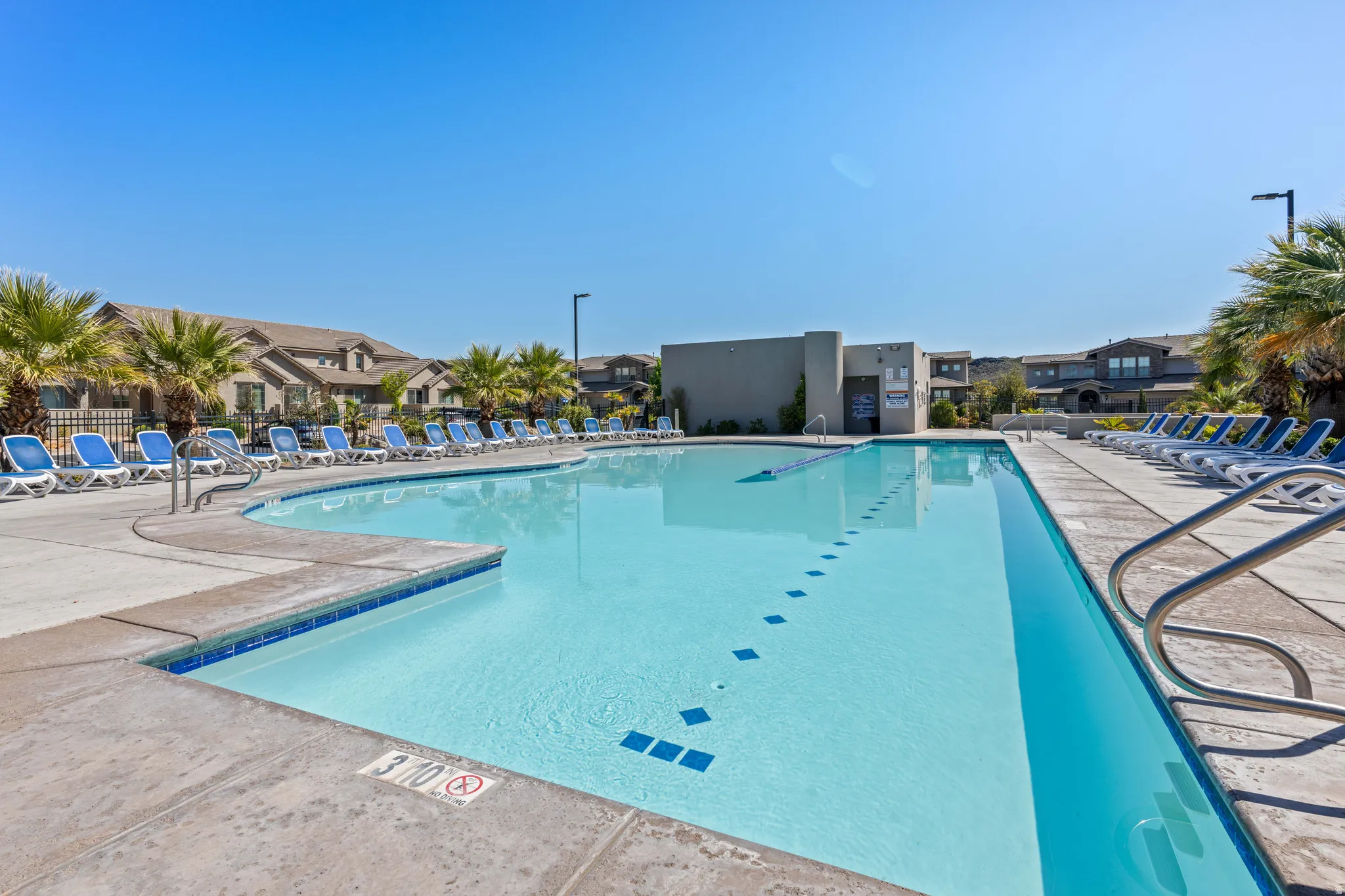Spacious swimming pool featuring a curved concrete deck, integrated steps, and perimeter lounge seating