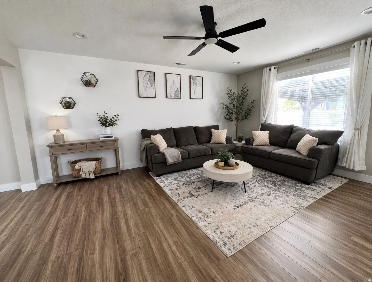 Spacious living area featuring wood-finish flooring, recessed lighting, and an expansive window with blinds