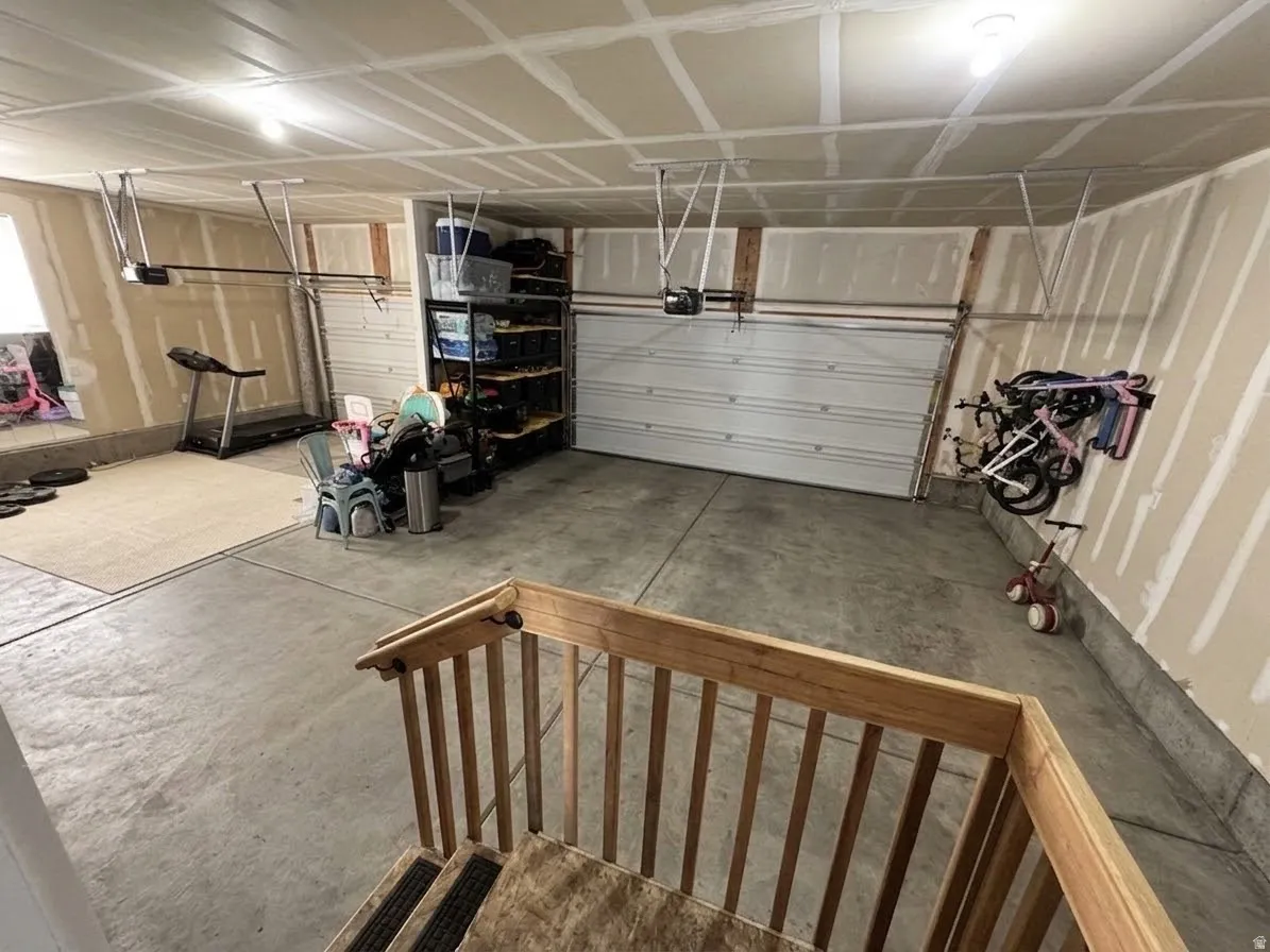 Spacious garage with concrete flooring, two overhead garage doors, and exposed ceiling joists