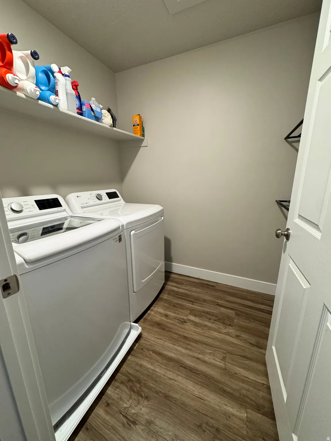 Dedicated utility space featuring wood-finish flooring, white baseboards, and neutral wall paint