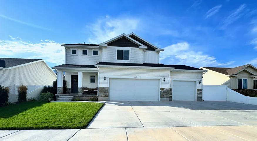 Two-story residence with a two-car garage, white siding, and stone accents