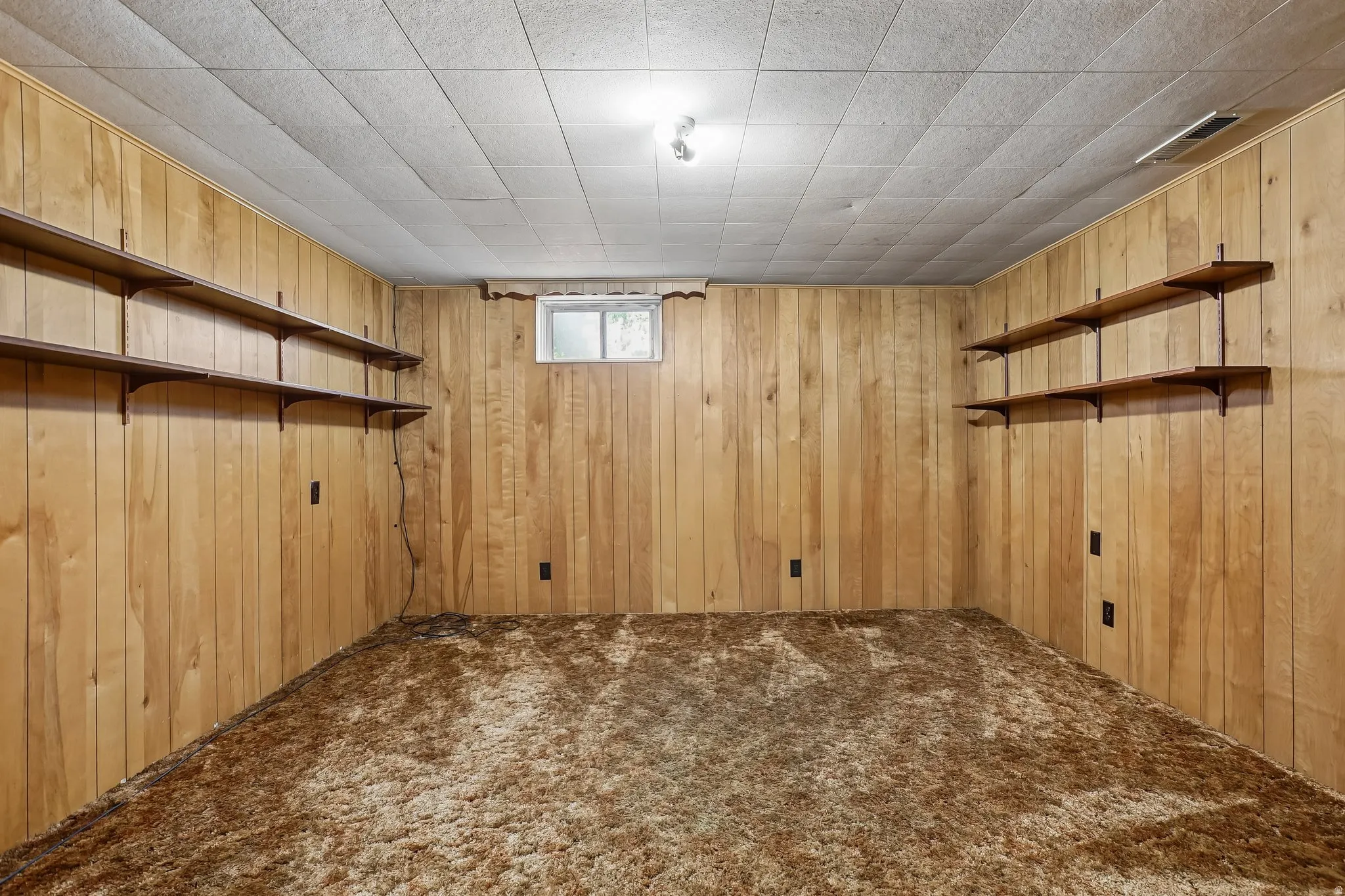 Room featuring wood-paneled walls and a drop-tile ceiling