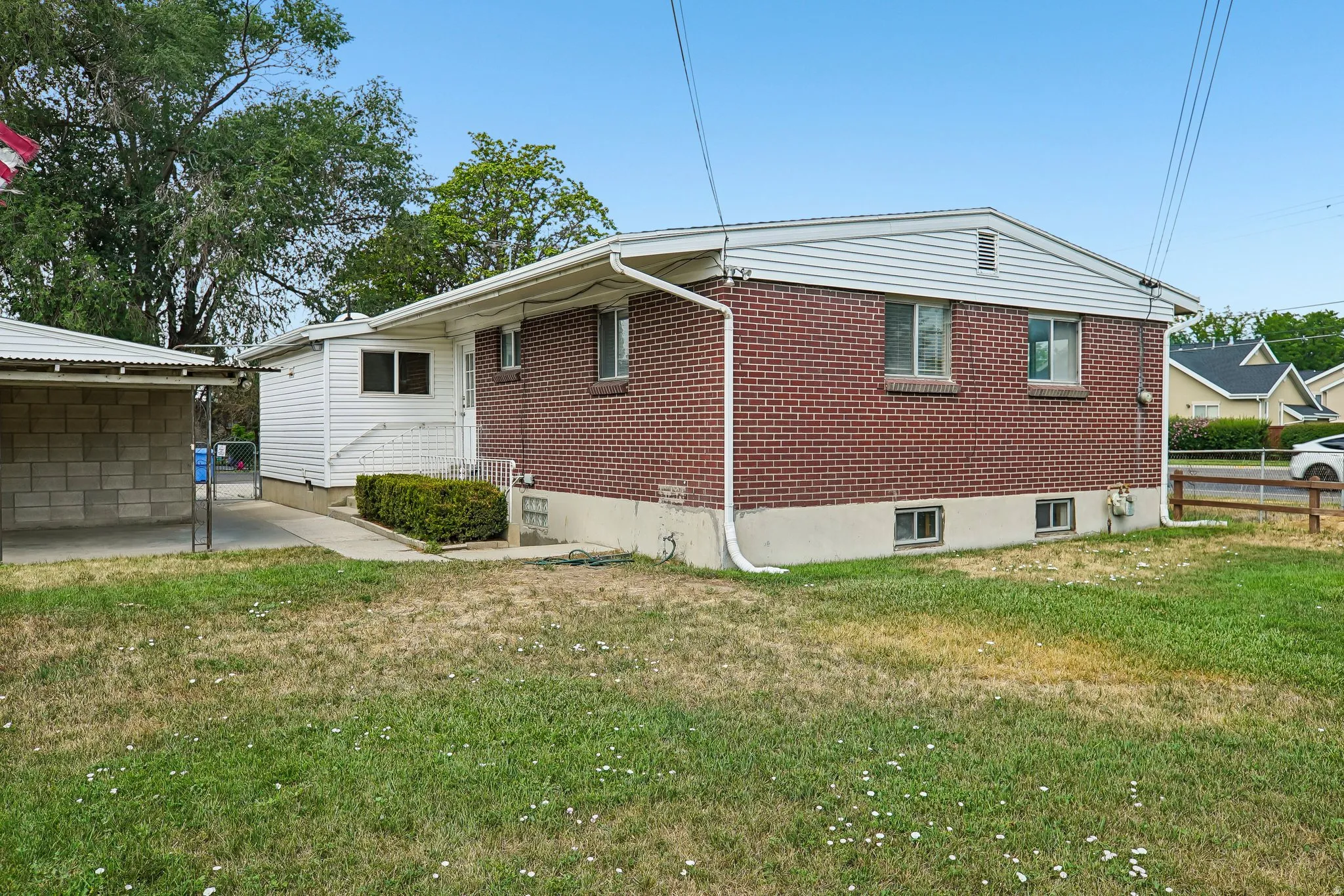 Brick exterior with white siding accents and a covered carport featuring concrete block walls
