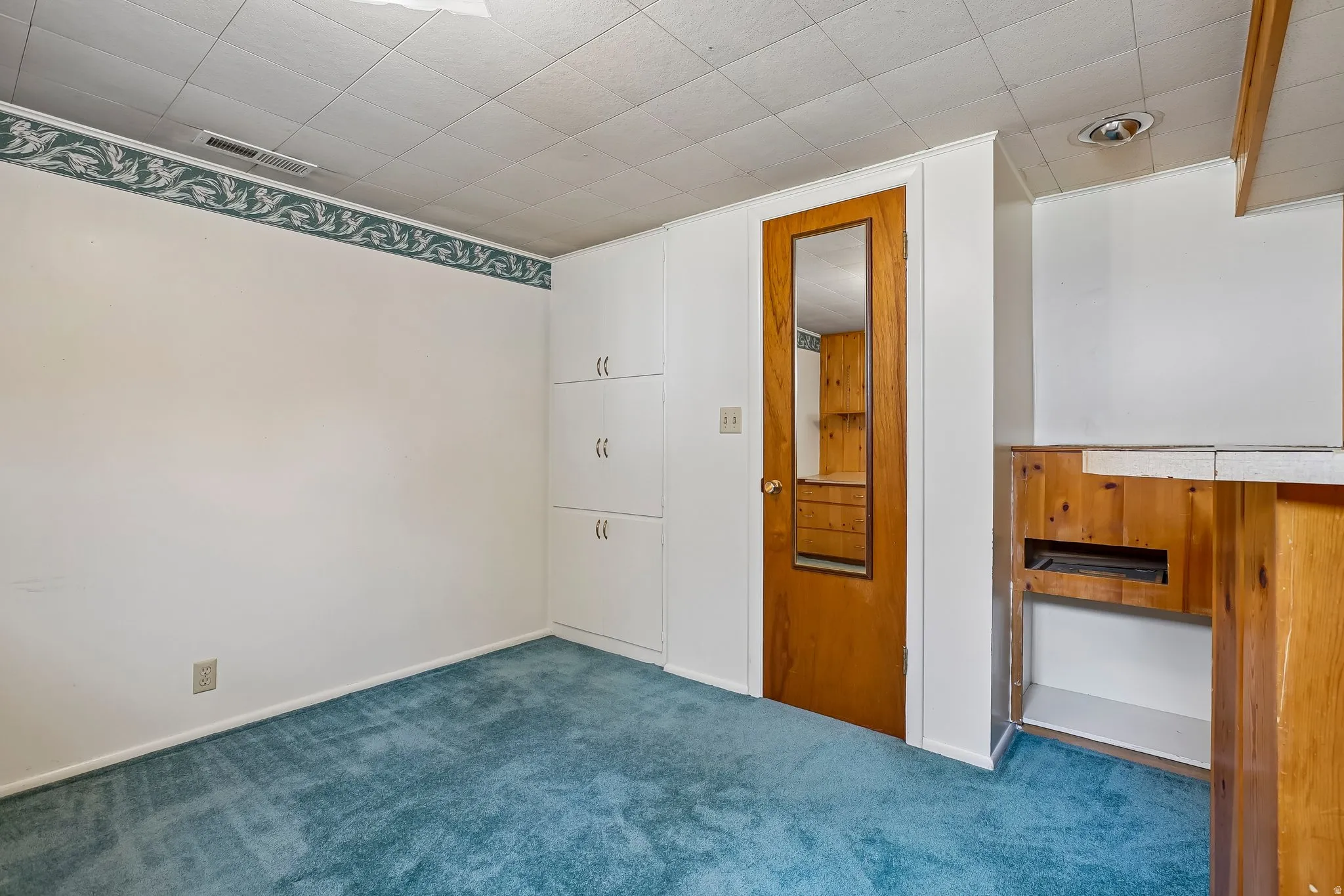 Room featuring blue carpeting, white walls, and a decorative border
