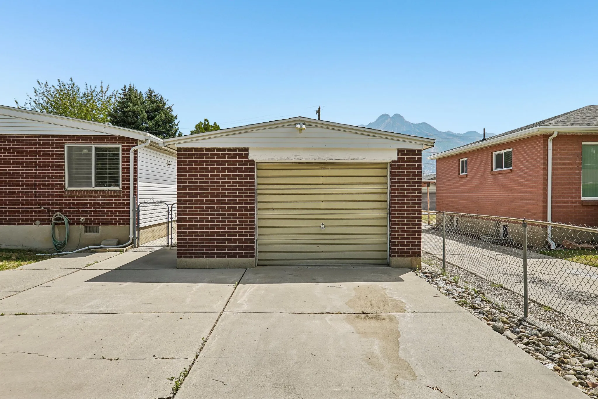 Detached garage featuring brick siding, a metal roll-up door, and a concrete driveway