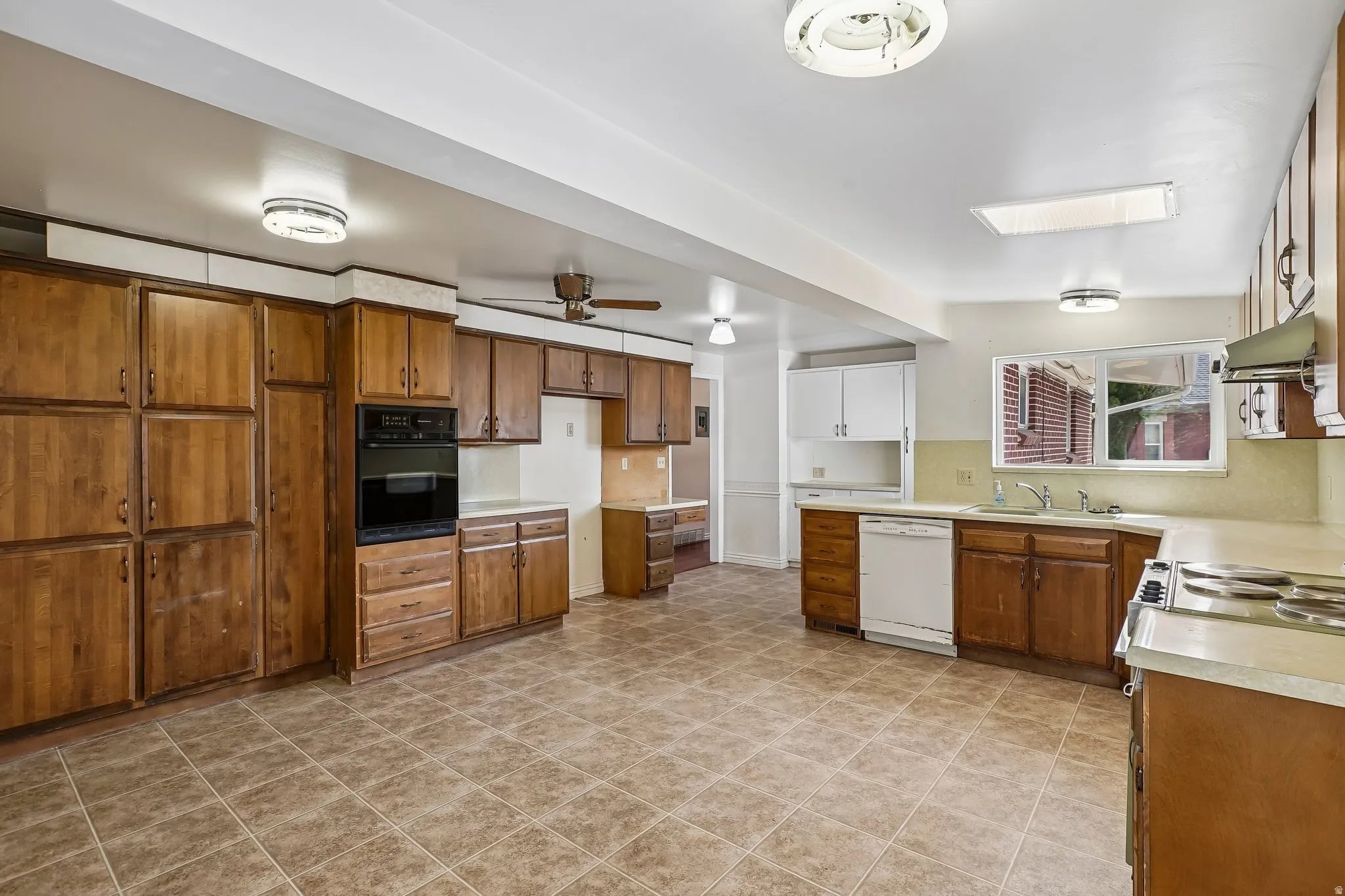 Expansive kitchen featuring wood cabinetry, built-in wall oven, integrated dishwasher, and tile flooring