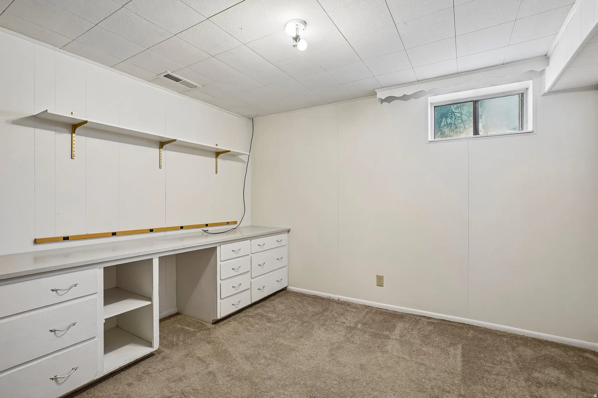 Room featuring extensive built-in cabinetry with white drawer fronts, a spacious countertop, and open shelving