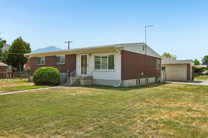 Brick and siding exterior featuring a covered entry, white railings, and a prominent front lawn