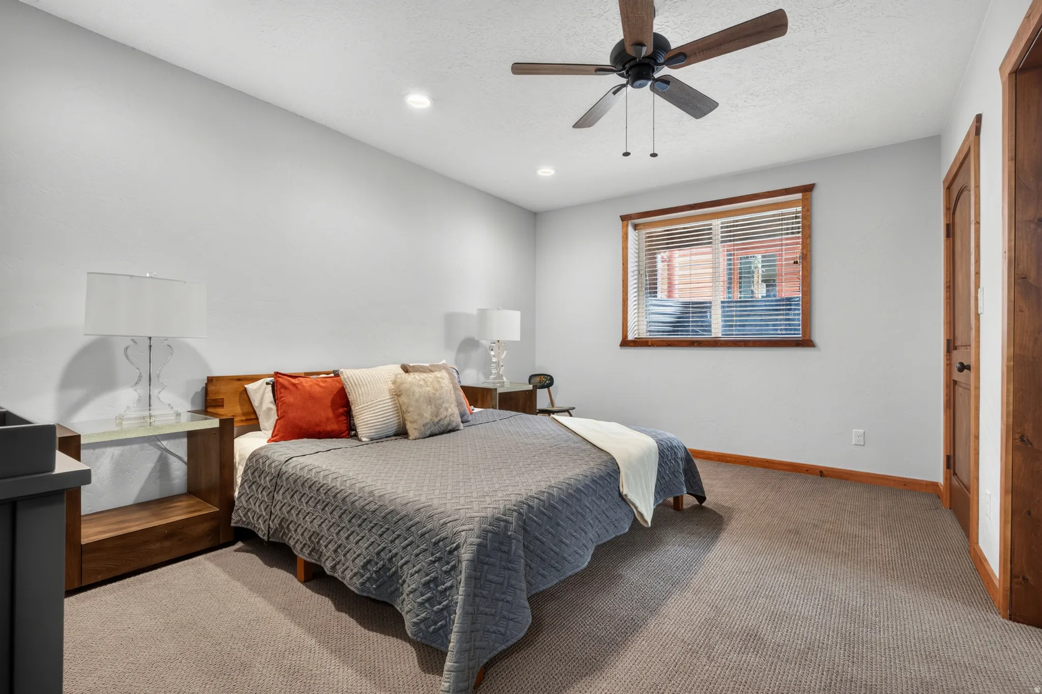 Carpeted room featuring a ceiling fan, recessed lighting, and a window with wood trim