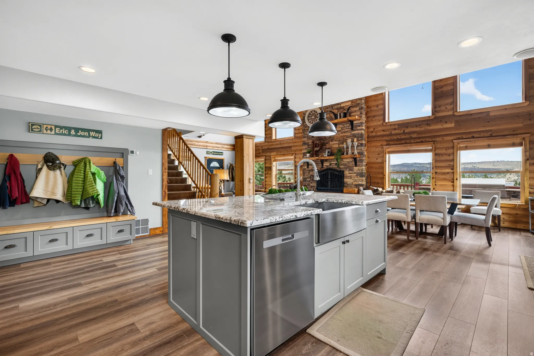 Open-concept kitchen featuring a large island with a stainless steel farmhouse sink, integrated dishwasher, and pendant lighting