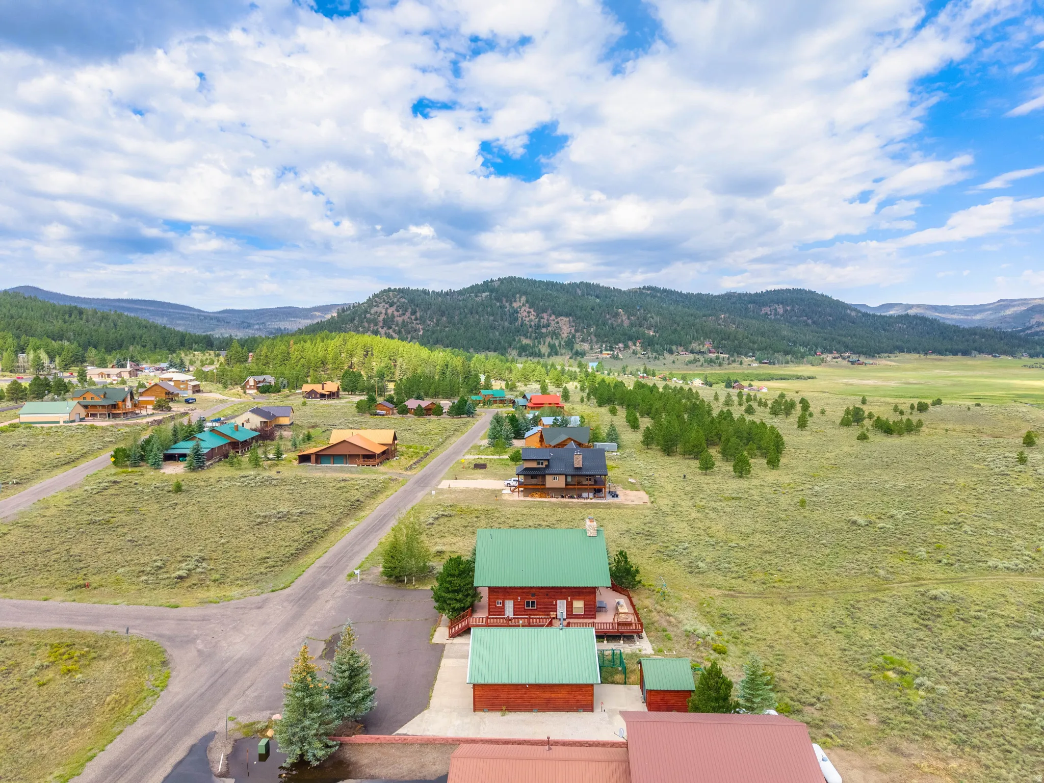 Aerial perspective showcasing a residential community nestled among rolling hills and expansive green pastures