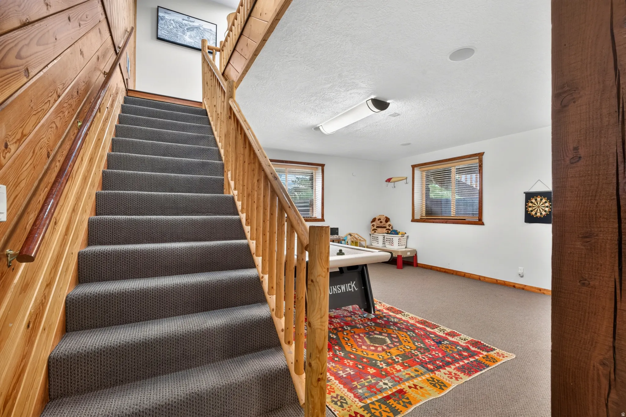 Carpeted staircase with natural wood paneling and railing