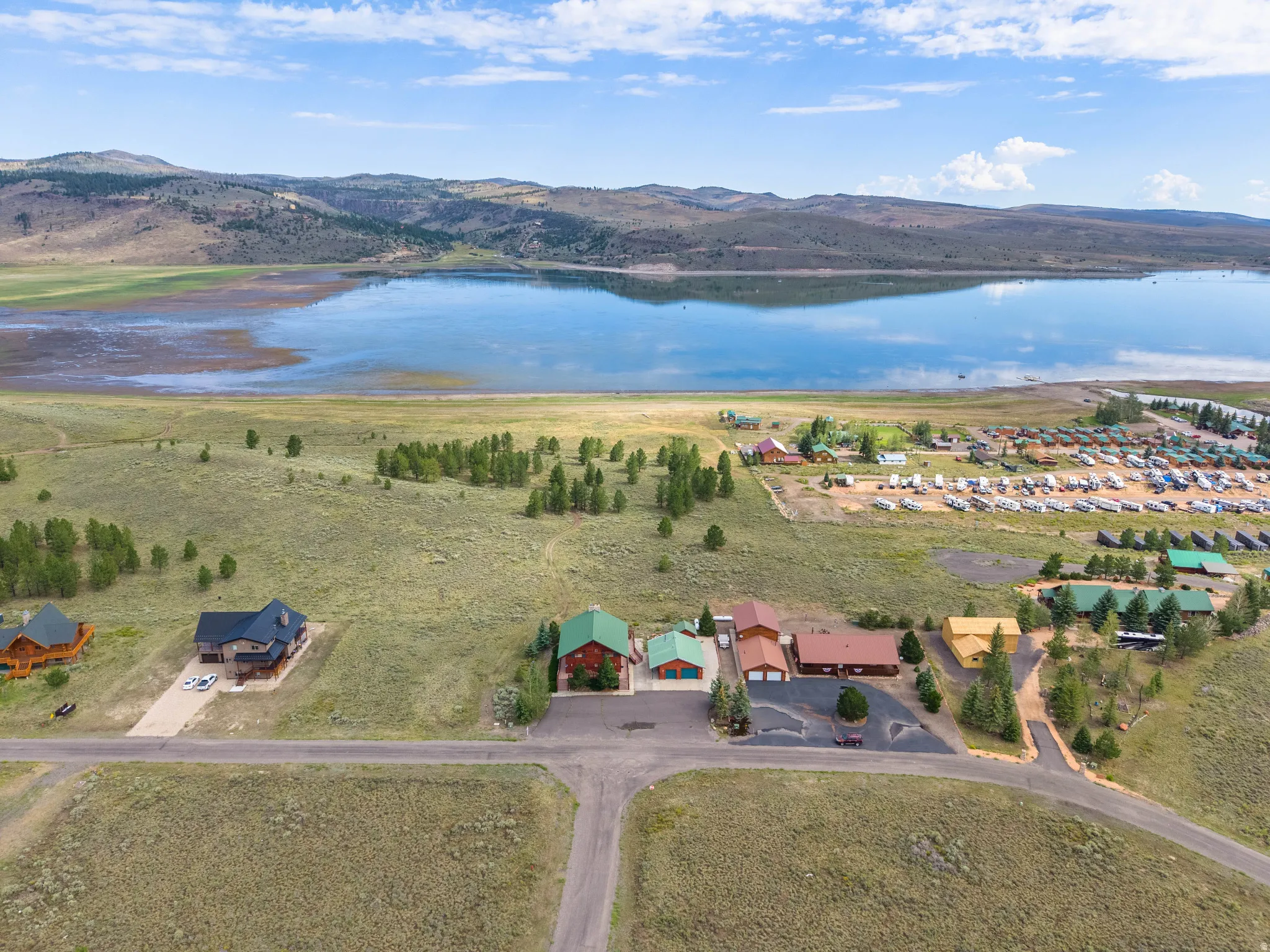 Expansive lakefront property featuring a serene lake, surrounding rolling hills, and scattered mature trees