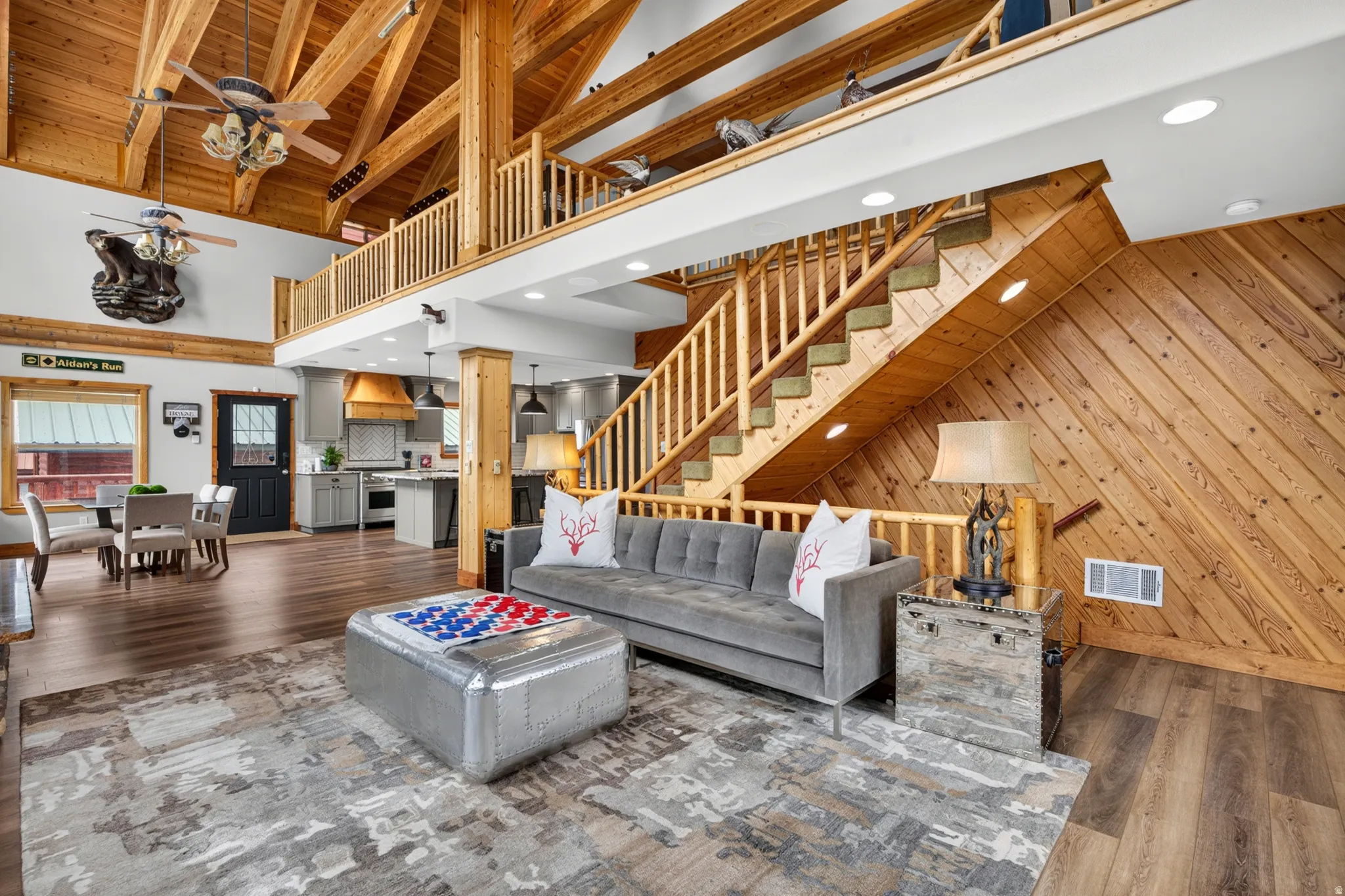 Spacious great room featuring soaring wood-beamed ceilings, a grand wooden staircase with a balustrade, and wood-finish flooring