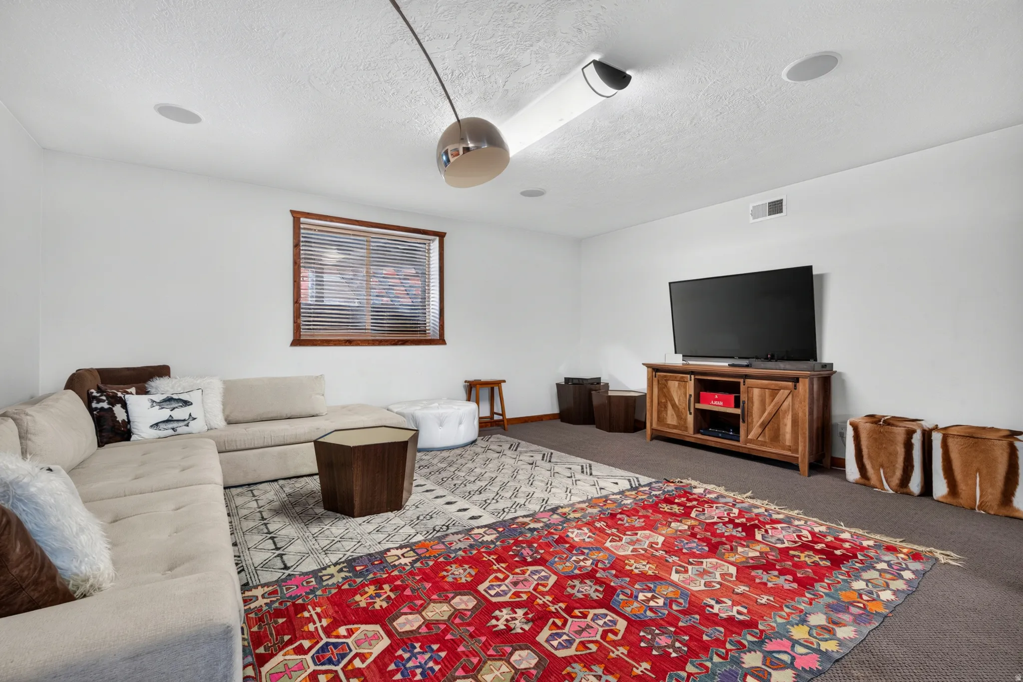 Spacious room featuring a wood-framed window with blinds, recessed ceiling lighting, a ceiling-mounted projector, and built-in ceiling speakers