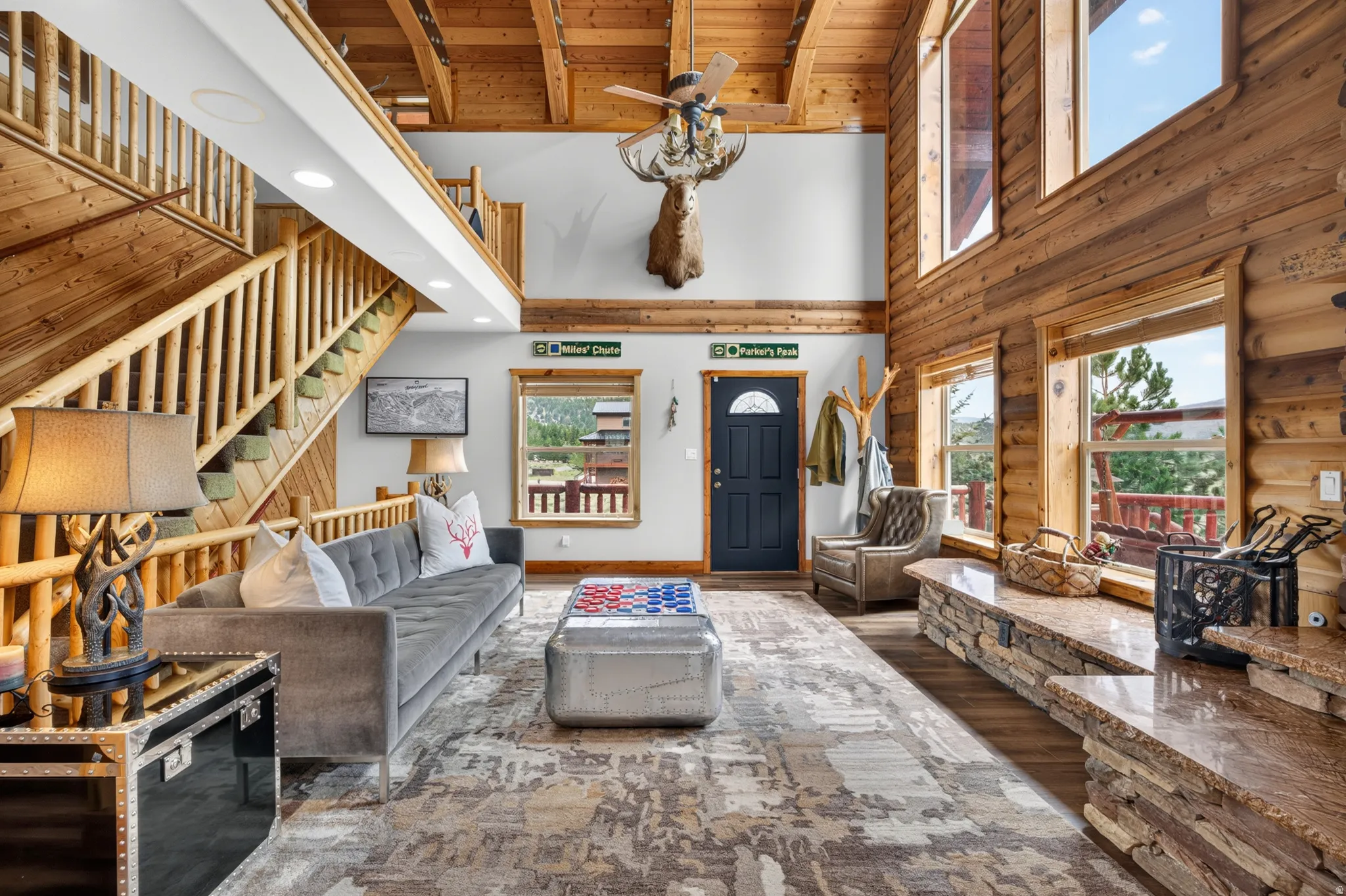 Expansive living area featuring vaulted wood ceilings, a prominent log staircase, and wood-finish flooring