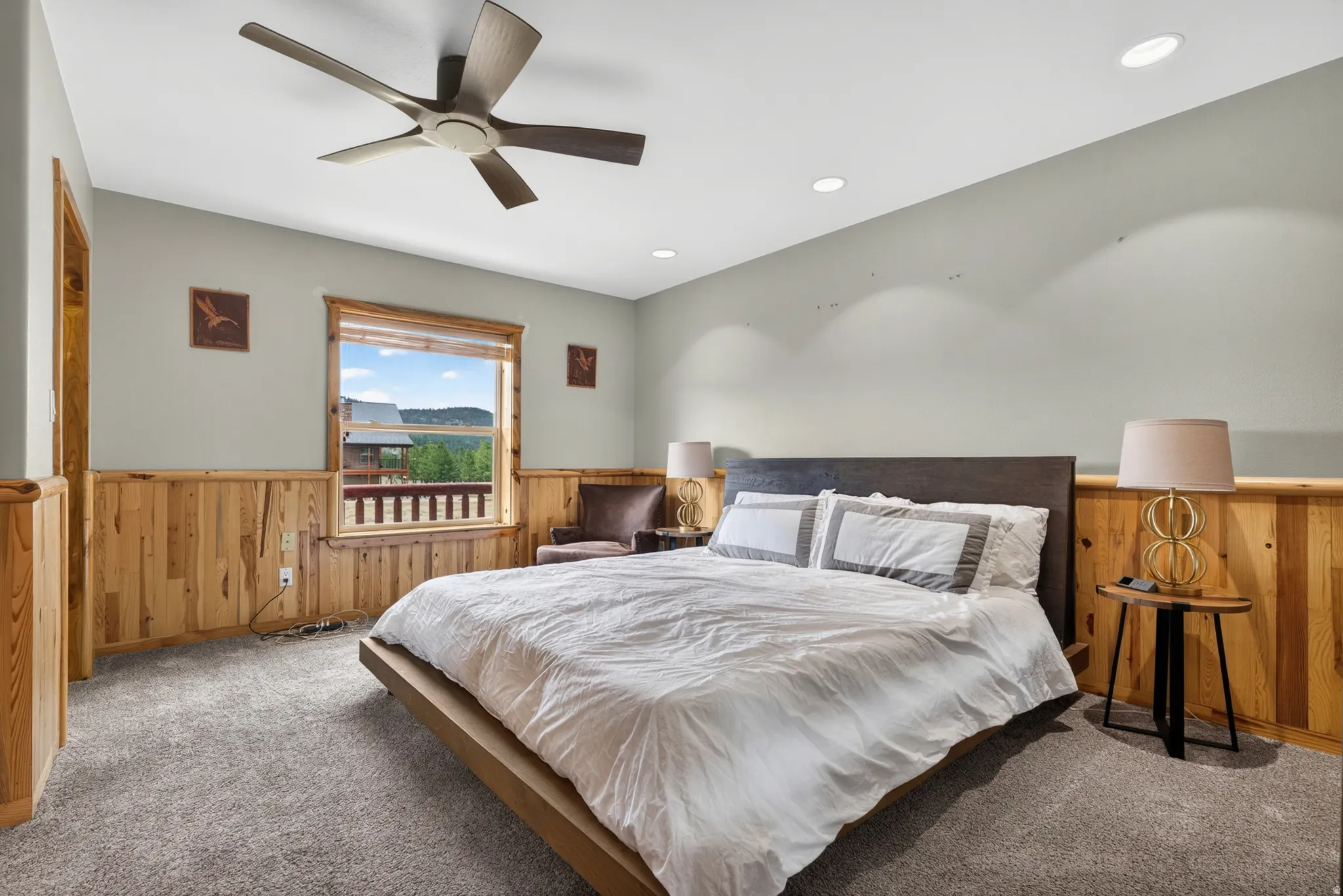 Bedroom featuring wood paneling, a large window with distant scenery, recessed lighting, and a ceiling fan