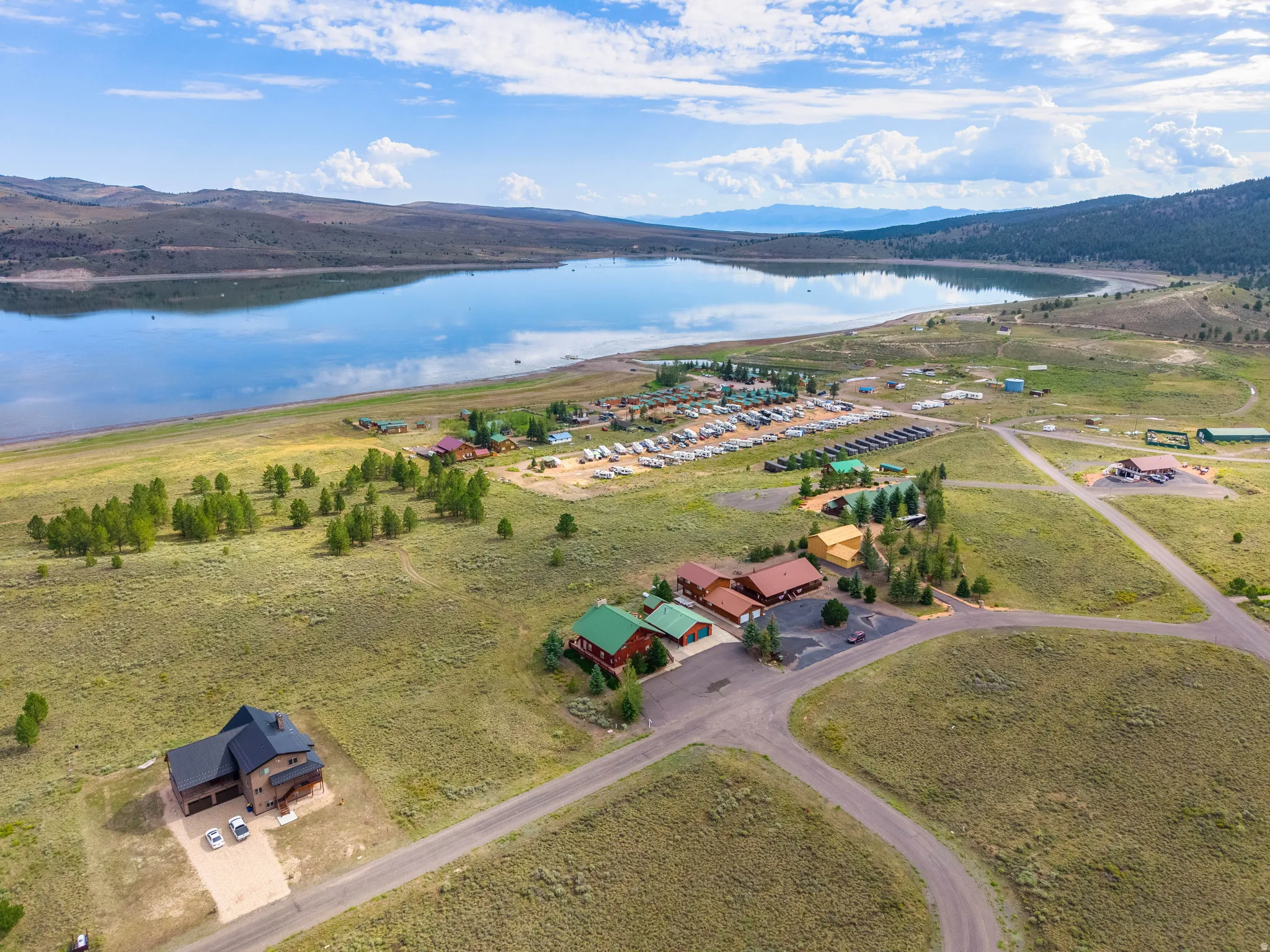 Expansive lakefront property featuring a contemporary residence, multiple commercial structures, and a large RV park