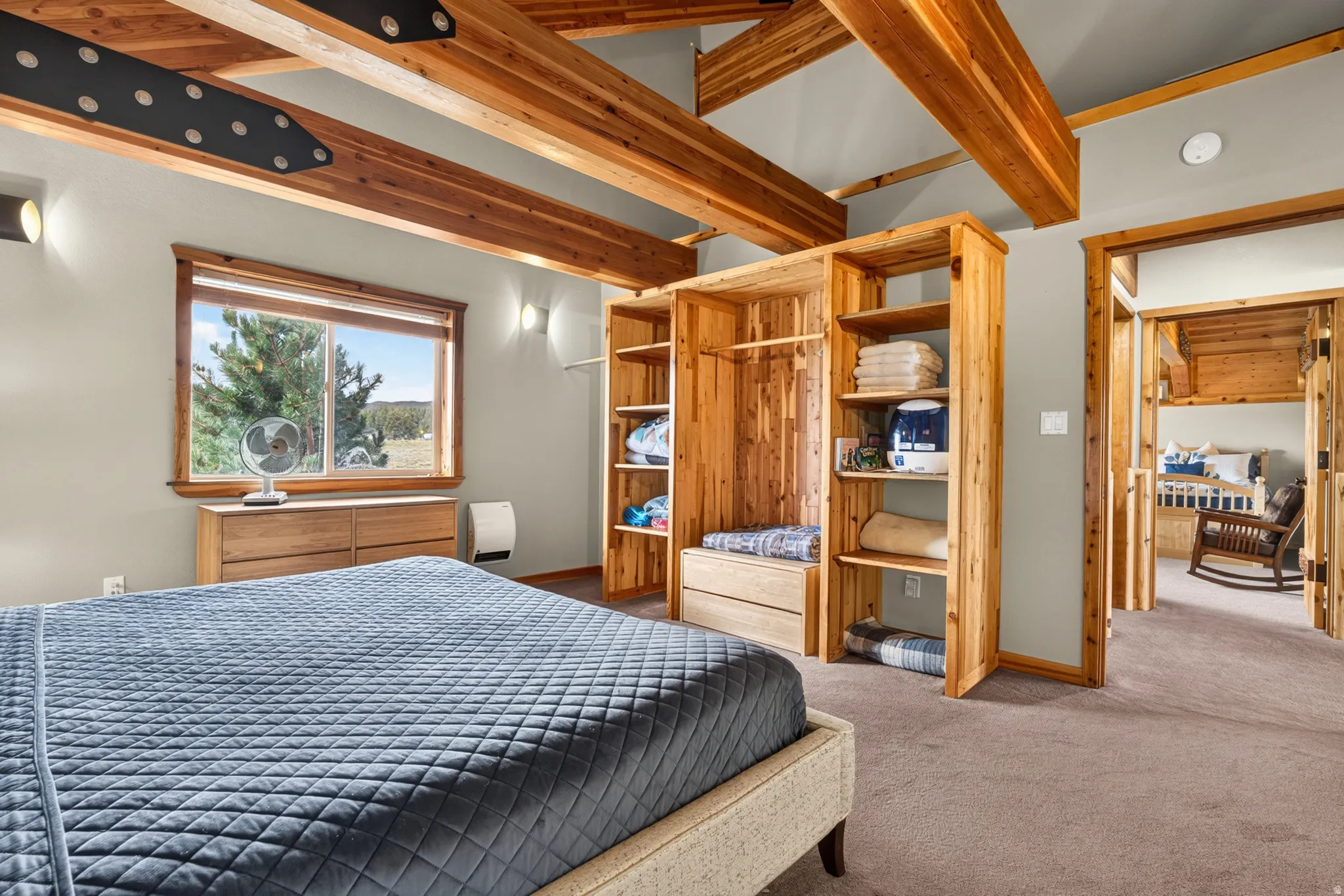 Bright room featuring exposed wood beams, a built-in wood closet system with shelving, and a large window