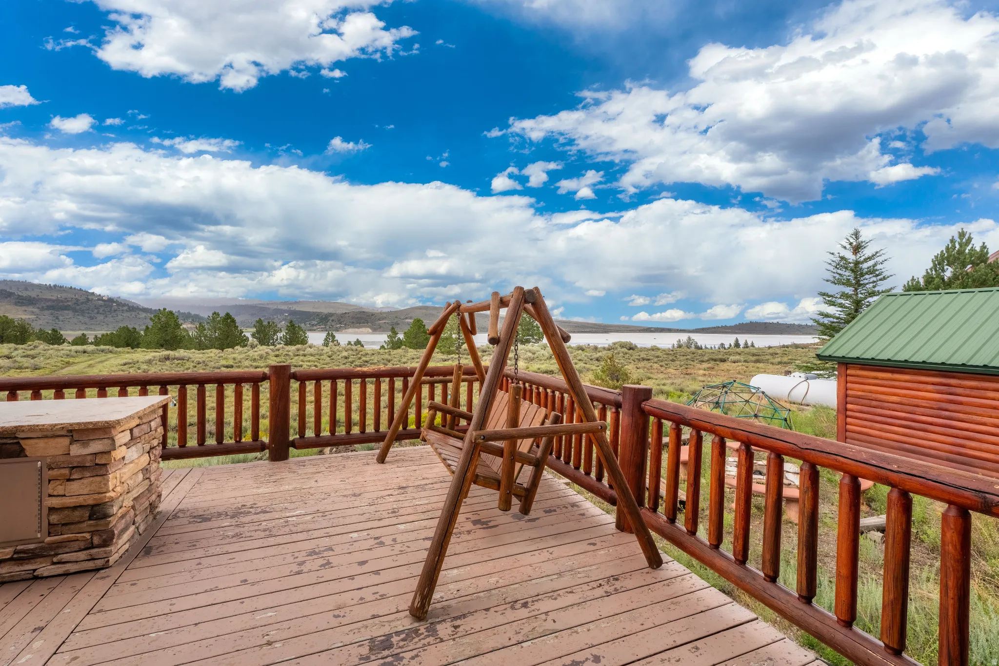 Expansive outdoor deck featuring wood-finish flooring and log railings
