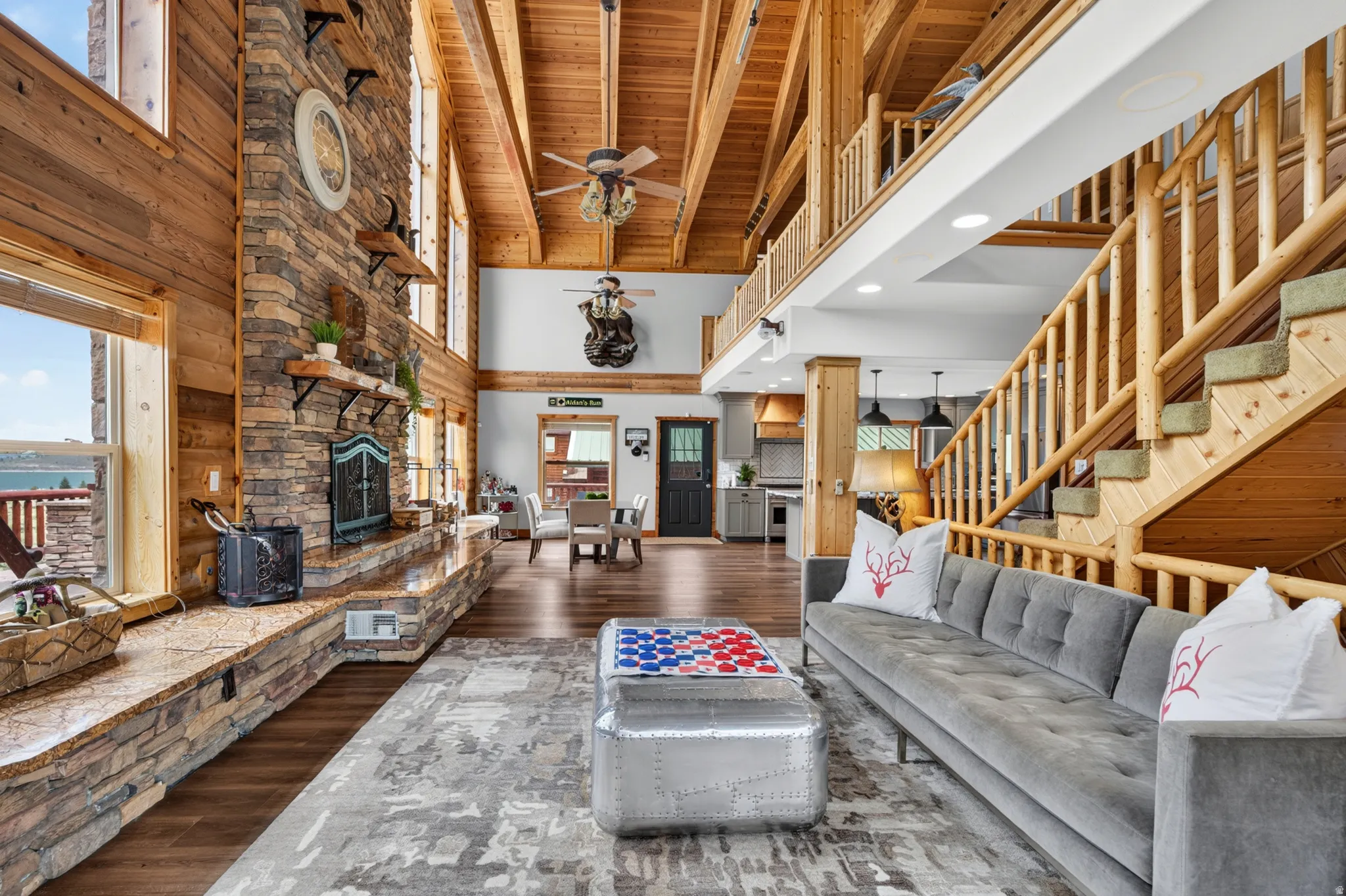 Vaulted wood-plank ceilings with exposed beams, a floor-to-ceiling stone fireplace, and wood-finish flooring define this spacious interior