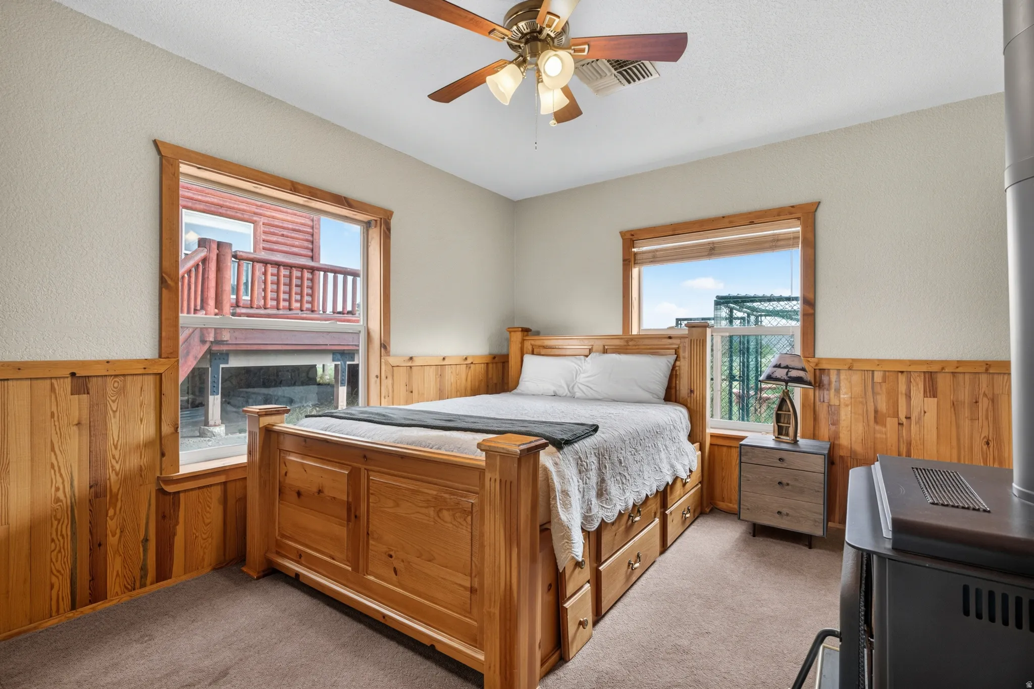 Carpeted room featuring wood paneling, trim, and two windows