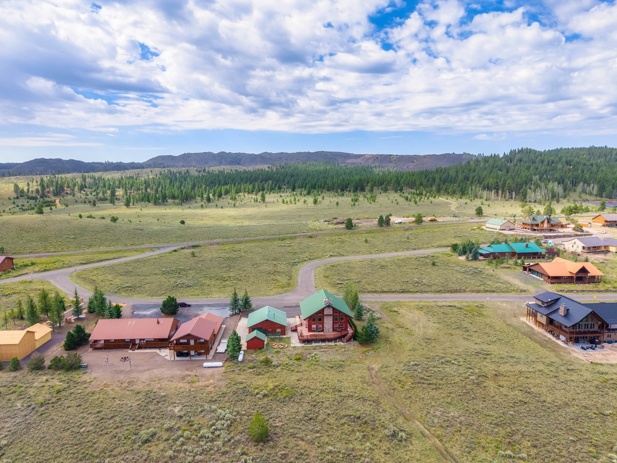 Expansive property featuring multiple structures, including a primary residence with a green roof, detached garage, and additional outbuildings