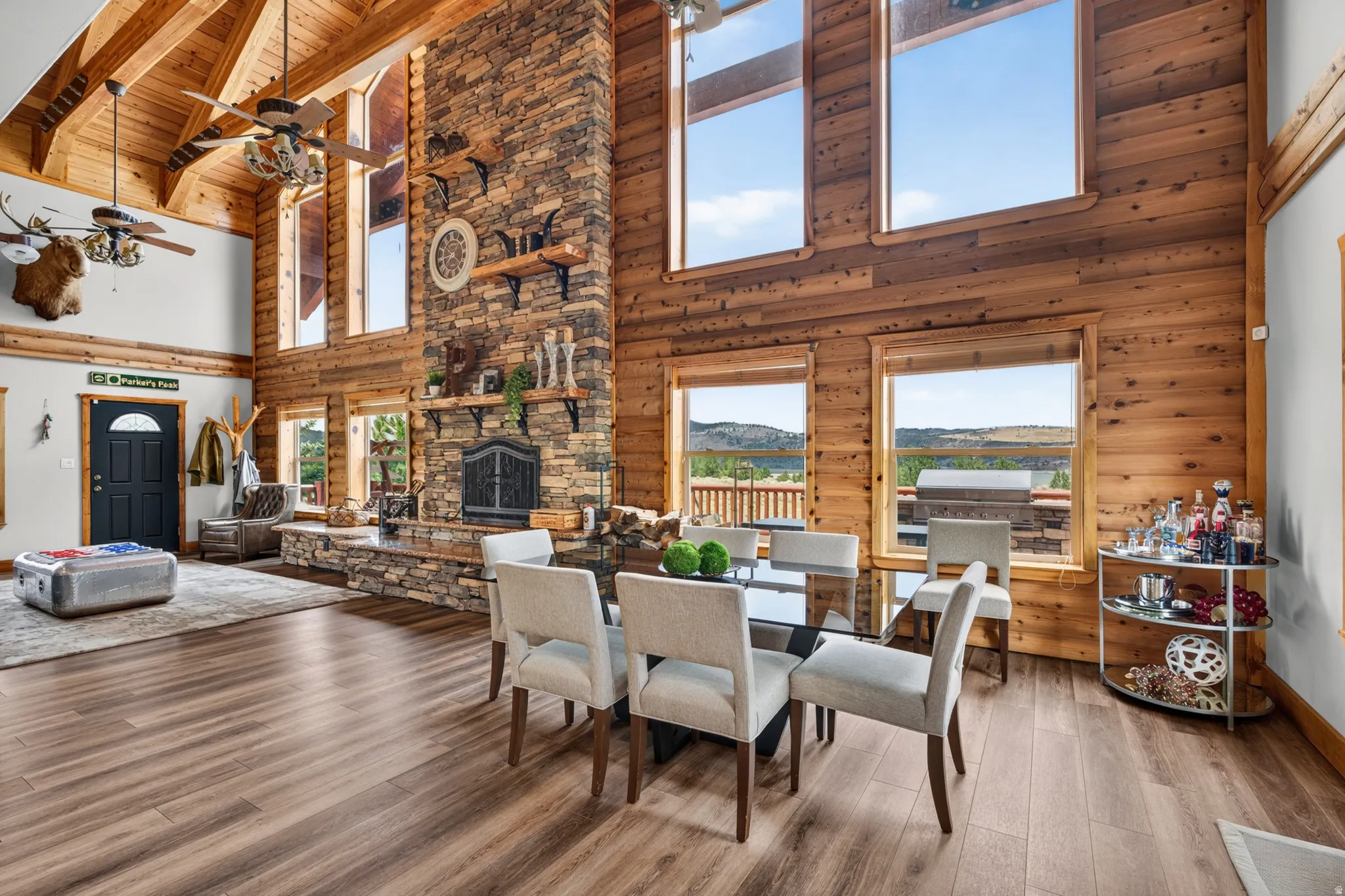 Great room featuring a vaulted wood-plank ceiling with exposed beams, a stacked stone fireplace with an integrated hearth, and wood-finish flooring