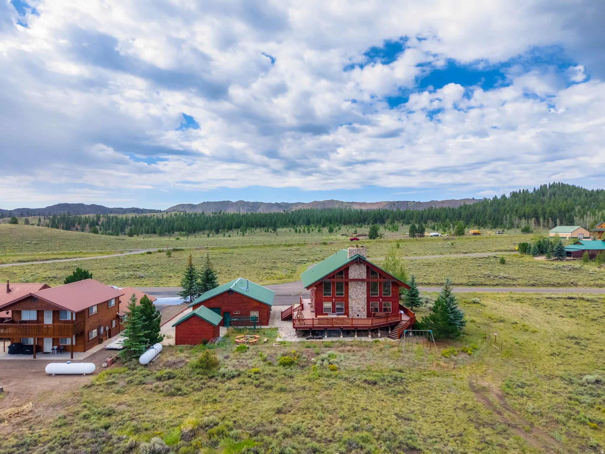 Rustic cabin-style residence featuring a stone-clad chimney and a green metal roof